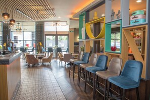 A modern interior with a bar area, seating, and a view through large windows. - Holiday Inn York City Centre by IHG (York)
