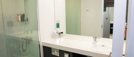 A modern bathroom with a glass-enclosed shower, a white sink, and a large mirror.