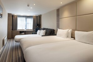 A hotel room with two beds, a desk, a chair, and a large window with curtains. - Holiday Inn York City Centre by IHG (York)