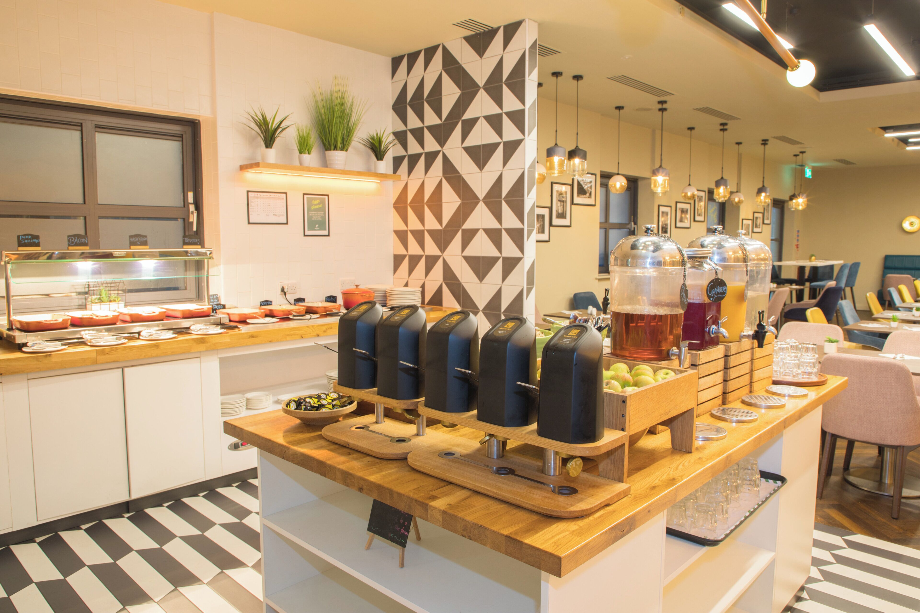 Una barra de desayuno con diversas opciones de comida, incluyendo frutas y un dispensador de bebidas.