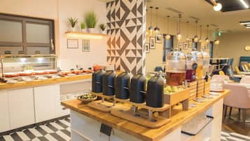 A breakfast bar with a variety of food options, including a selection of fruits and a beverage dispenser.