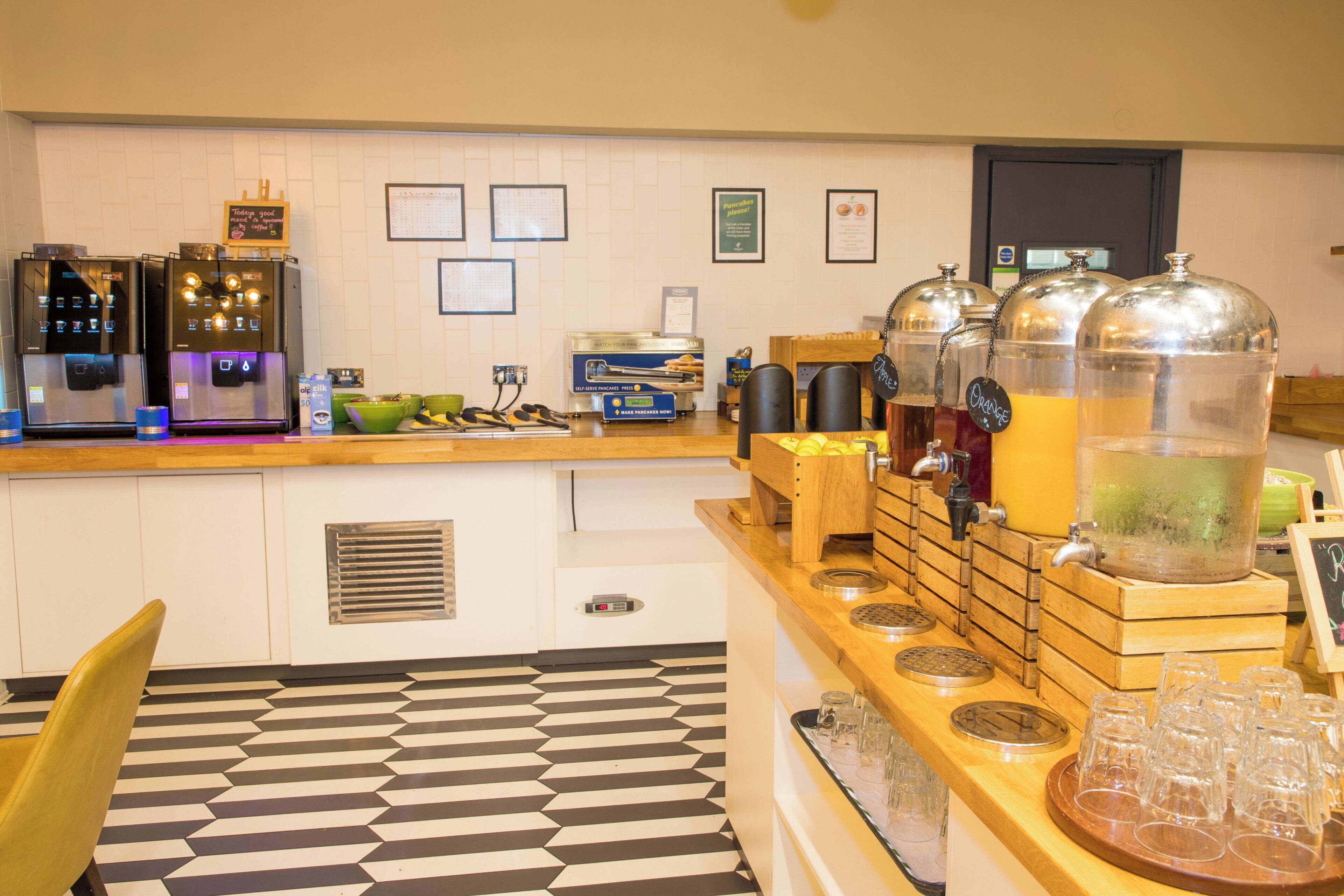 Un bar à petit-déjeuner équipé de machines à café, d’un espace où l’on peut se servir soi-même pour préparer des crêpes, et de distributeurs de boissons.