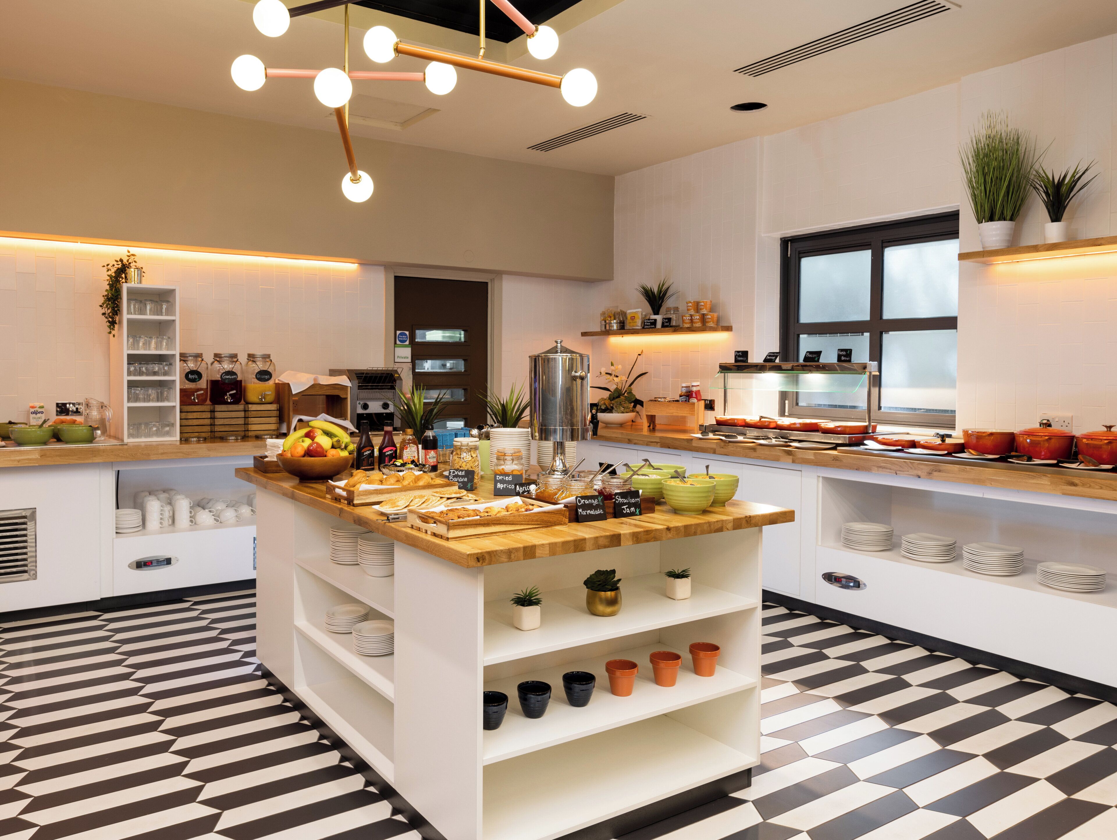 A modern kitchen with a central island, various food items, and a checkered floor pattern.