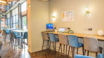 A bar area with a wooden counter, bar stools, and a laptop.