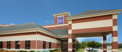 A Sleep Inn hotel with a registration sign, parking area, and a clear blue sky.