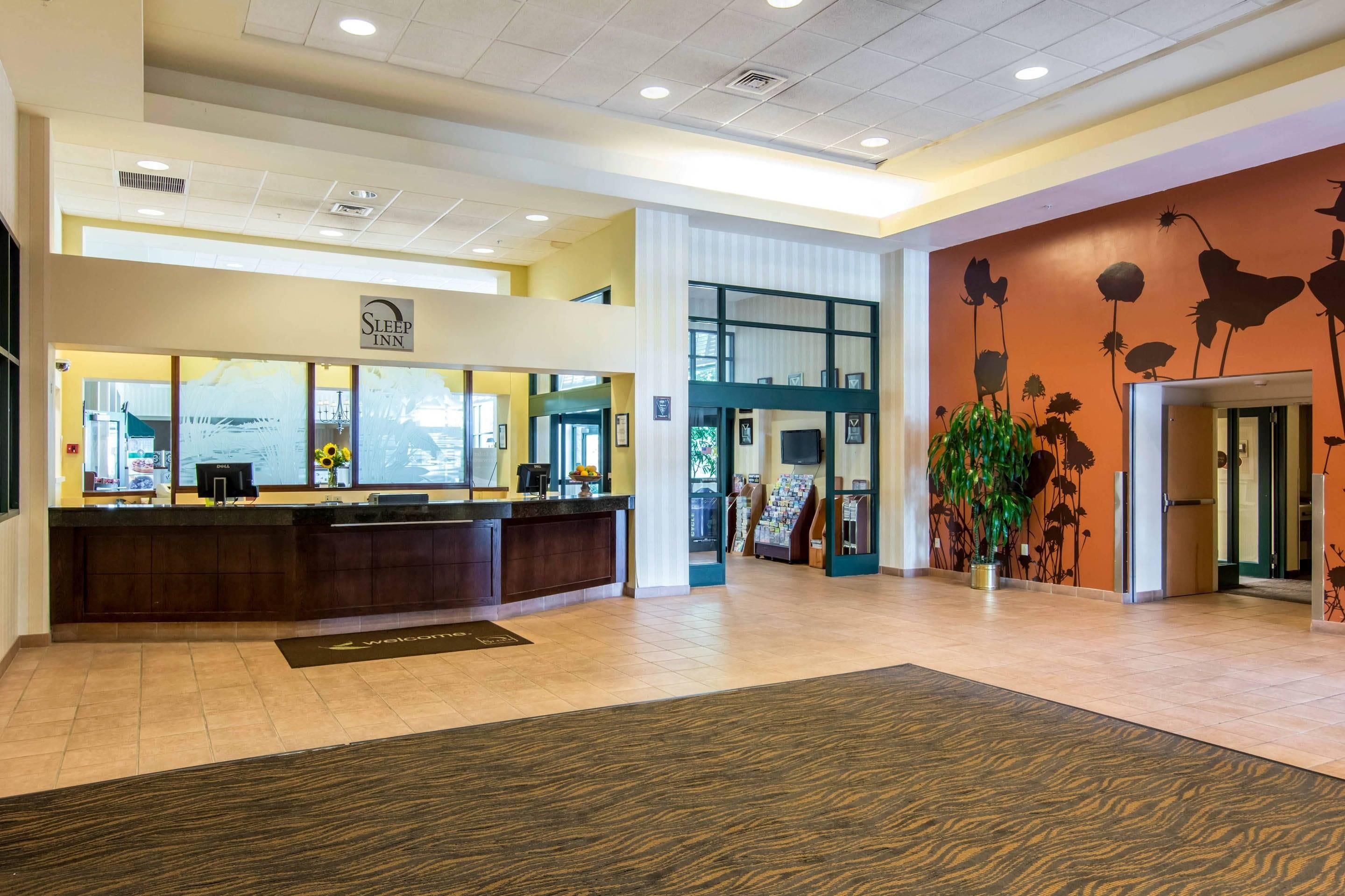 A hotel reception area with a reception desk, a large window, and a wall with a floral mural.