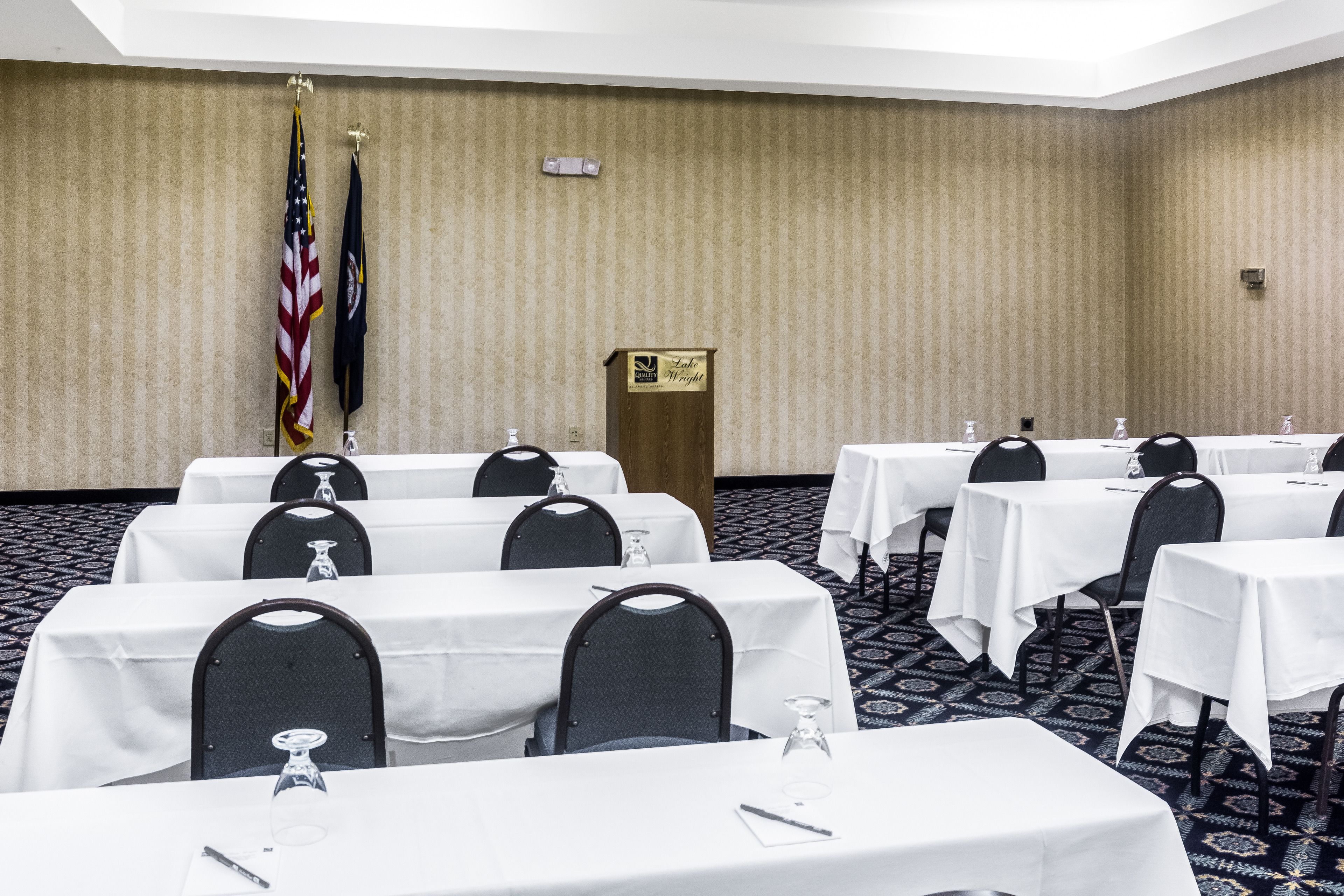 A conference room with multiple tables, chairs, and flags.