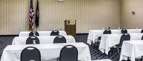 A conference room with multiple tables, chairs, and flags.