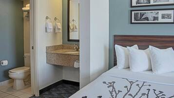 Habitación de hotel con cama, baño con inodoro, lavamanos y toallas.