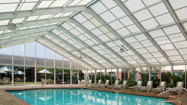 A covered swimming pool with lounge chairs and umbrellas. - Sleep Inn Lake Wright - Norfolk Airport (Norfolk)