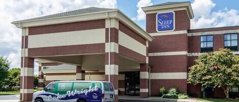A Sleep Inn hotel with a parking lot and a service van parked in front.