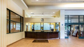 A hotel reception area with a reception desk, a 'Welcome' mat, and a sign for 'Sleep Inn'. - Sleep Inn Lake Wright - Norfolk Airport (Norfolk)
