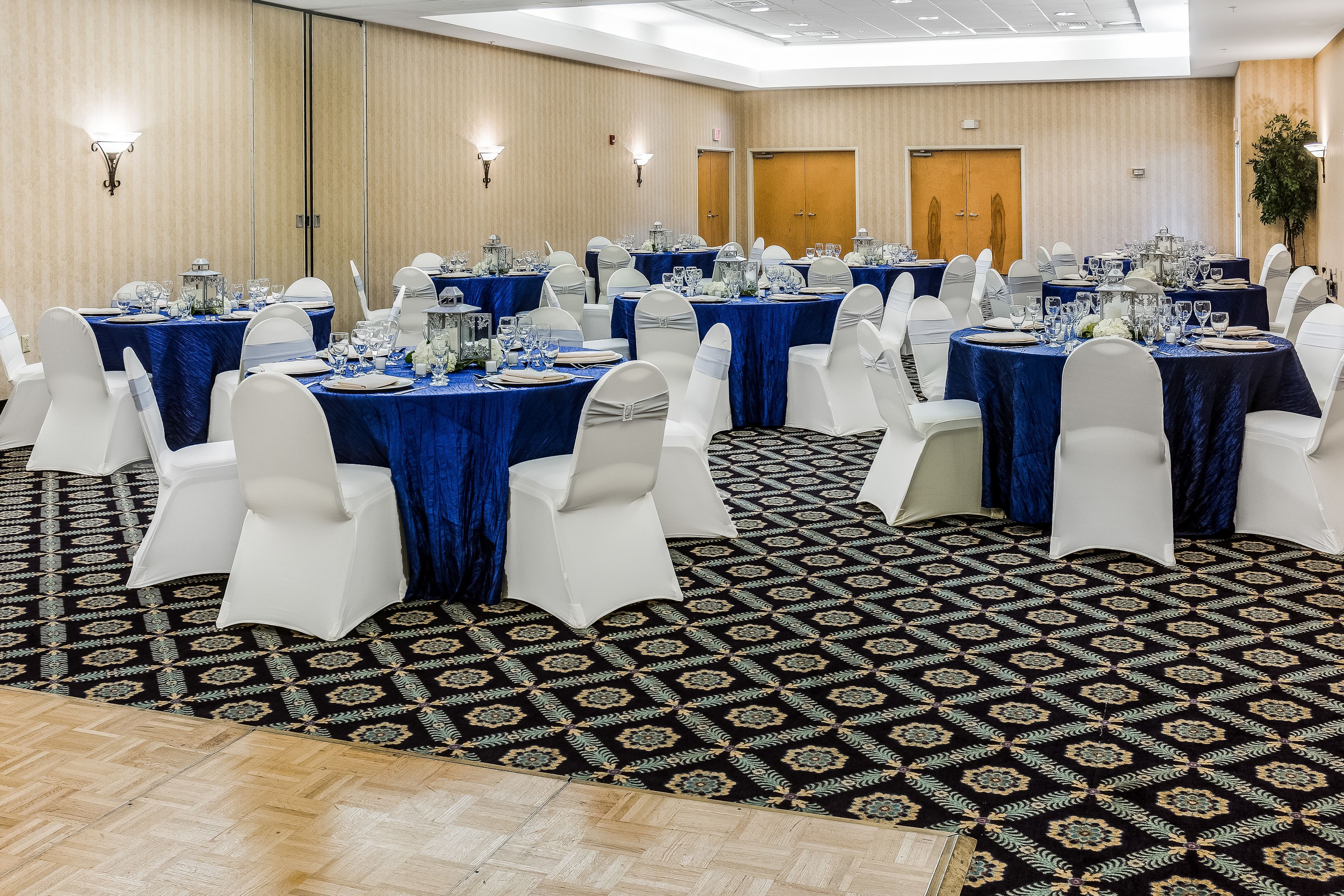 A conference room with round tables, white chairs, and blue tablecloths.
