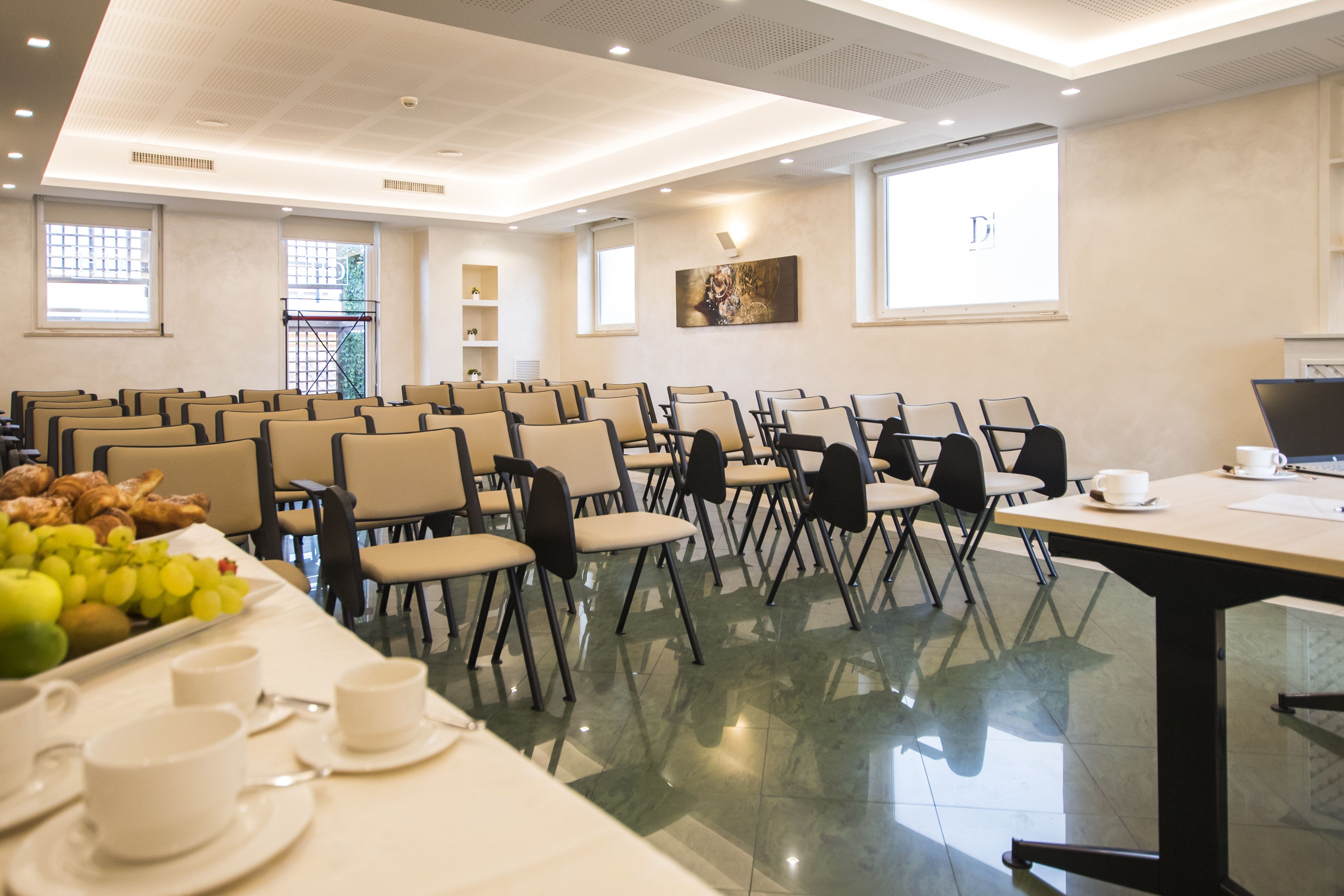 A conference room with rows of chairs, a table with breakfast items, and a projector screen.