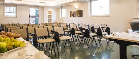 A conference room with rows of chairs, a table with breakfast items, and a projector screen.