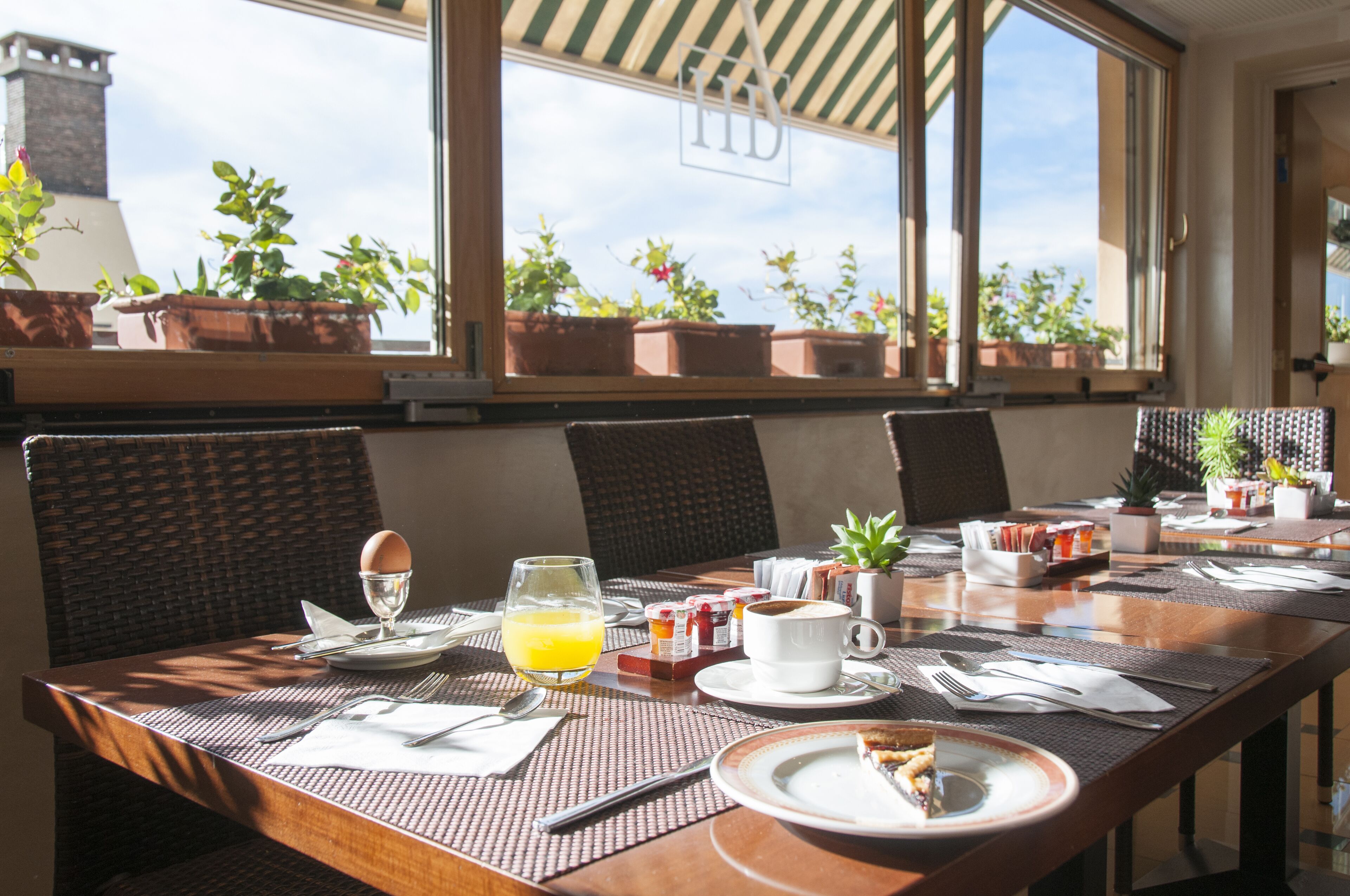 A breakfast table set with plates, cutlery, a glass of orange juice, and a cup of coffee.