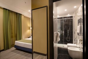 Een hotelkamer met een bed, een badkamer met douche, toilet en wastafel.