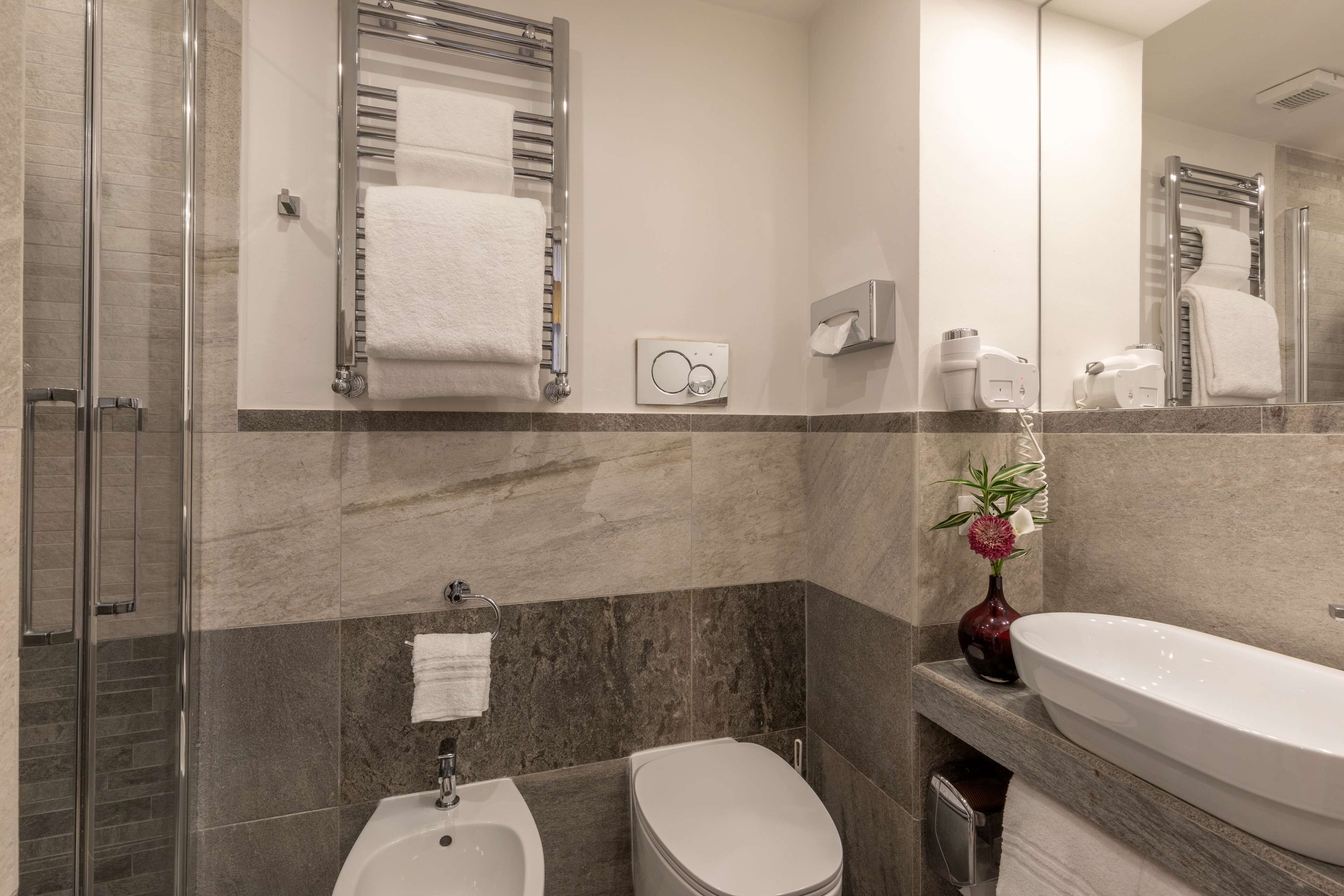 Un baño moderno con cabina de ducha de vidrio, un bidé, un lavamanos y un espejo.