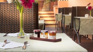 Una mesa con mantel blanco, un florero con flores y una bandeja con frascos.