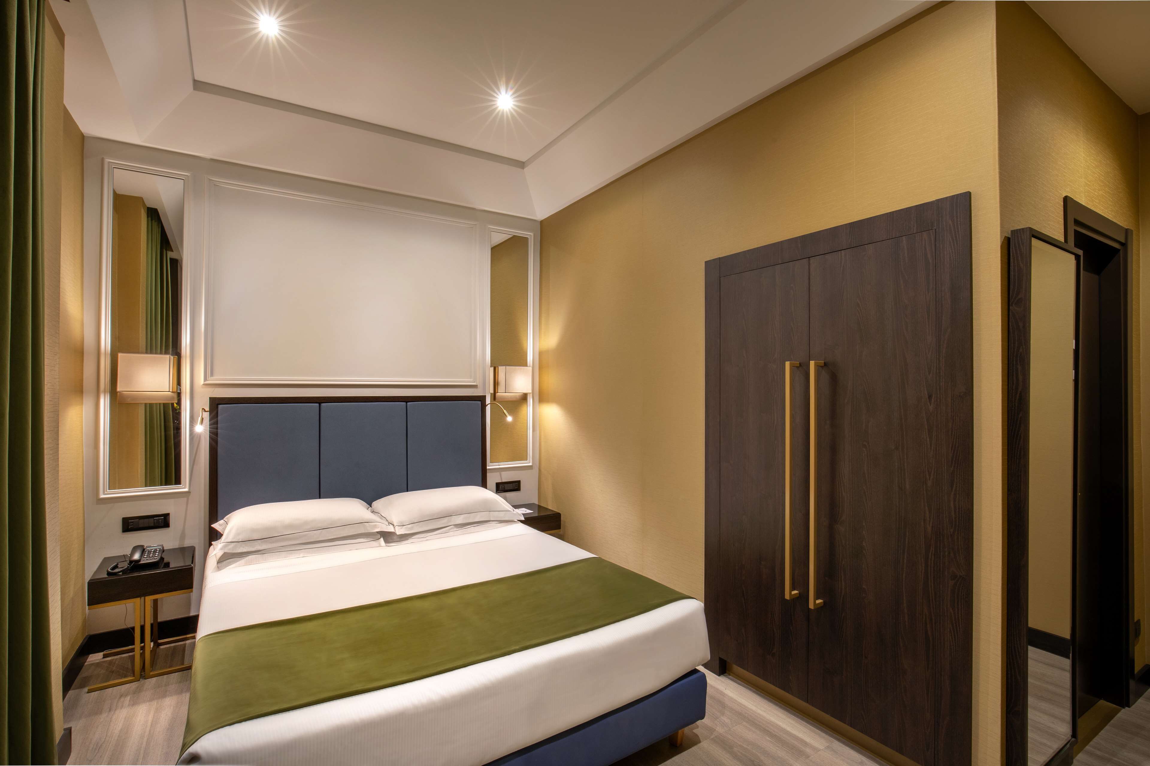 A hotel room with a bed, bedside table, lamp, and wardrobe.