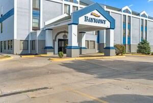Un hotel Baymont con entrada despejada, un corredor cubierto y un estacionamiento.