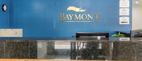 A reception desk with a blue wall and a logo that reads "Baymont."