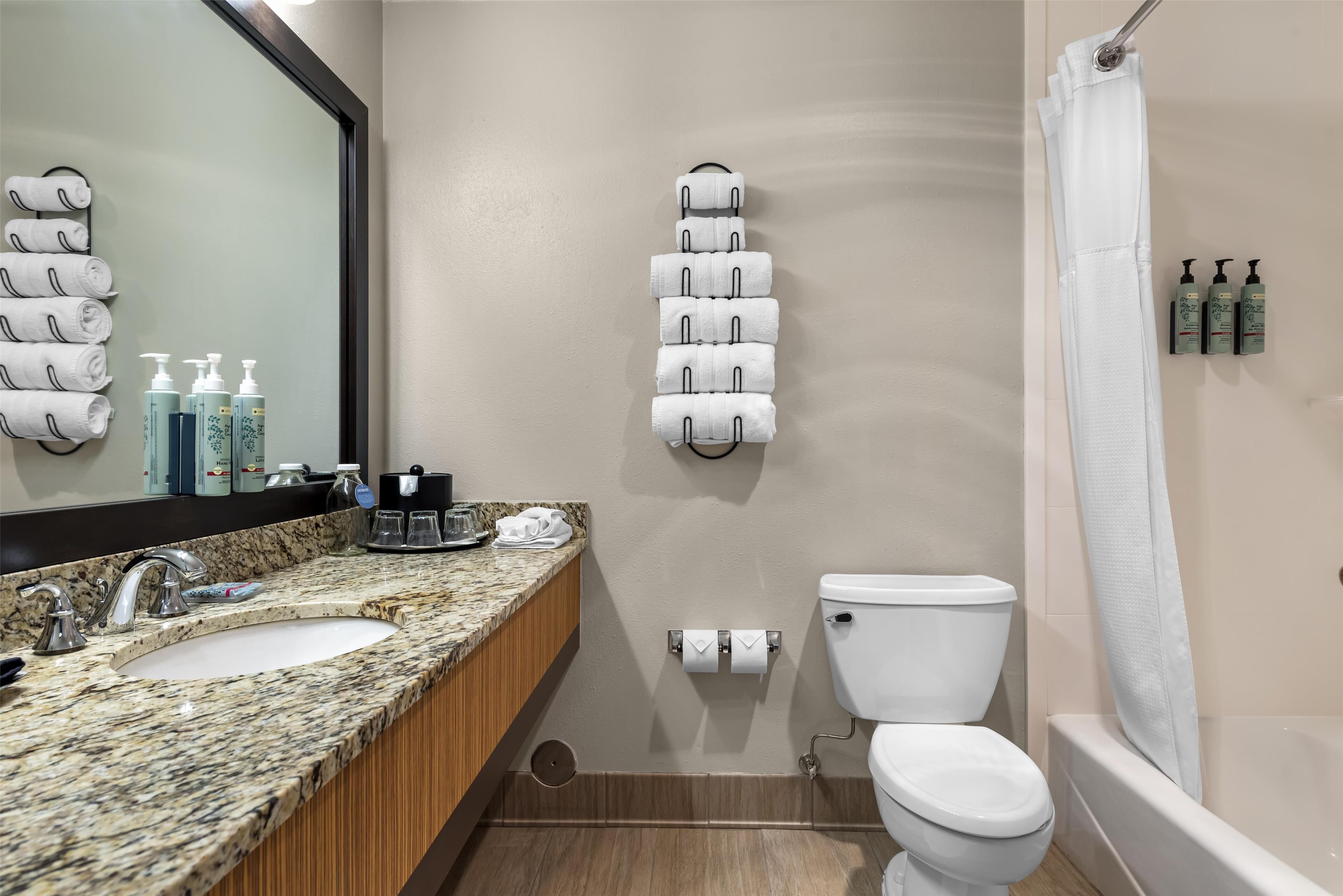 A bathroom with two sinks, a toilet, a bathtub, and a towel rack with folded towels.
