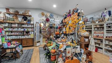 A store with various items on shelves and tables, including hats, bags, and Halloween decorations.