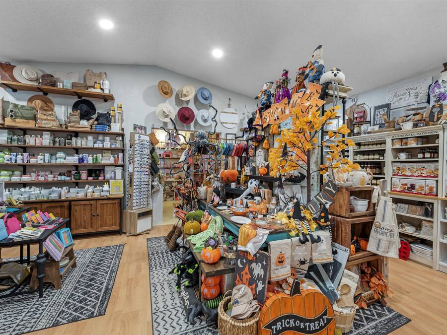 A store with various items on shelves and tables, including hats, bags, and Halloween decorations.