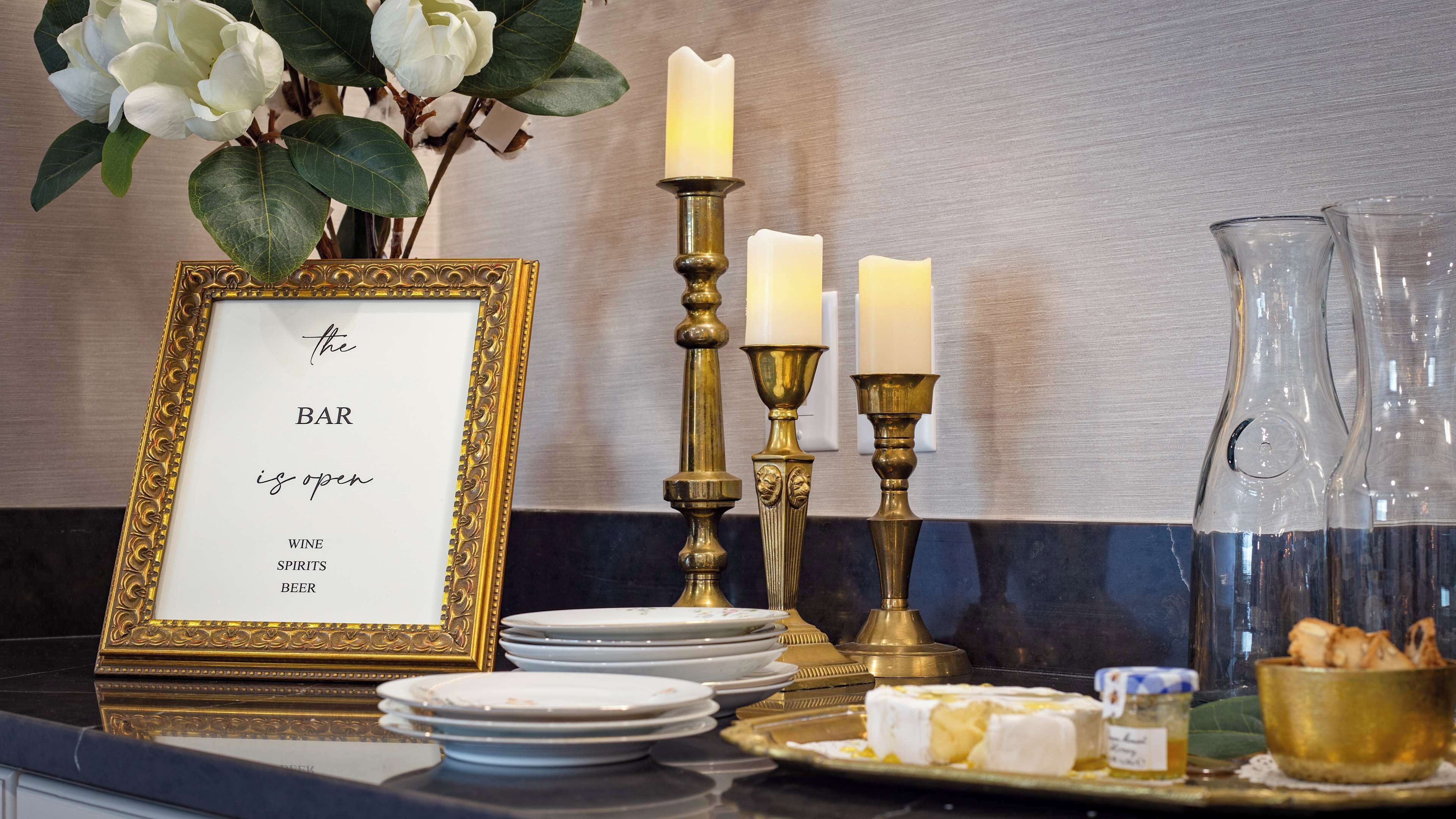 A table with a framed sign, candles, plates, and a pitcher.