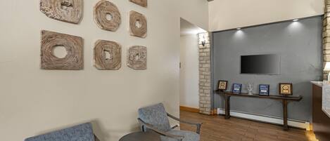 A lobby with a stone wall, a flat-screen TV, and a bench with framed awards.
