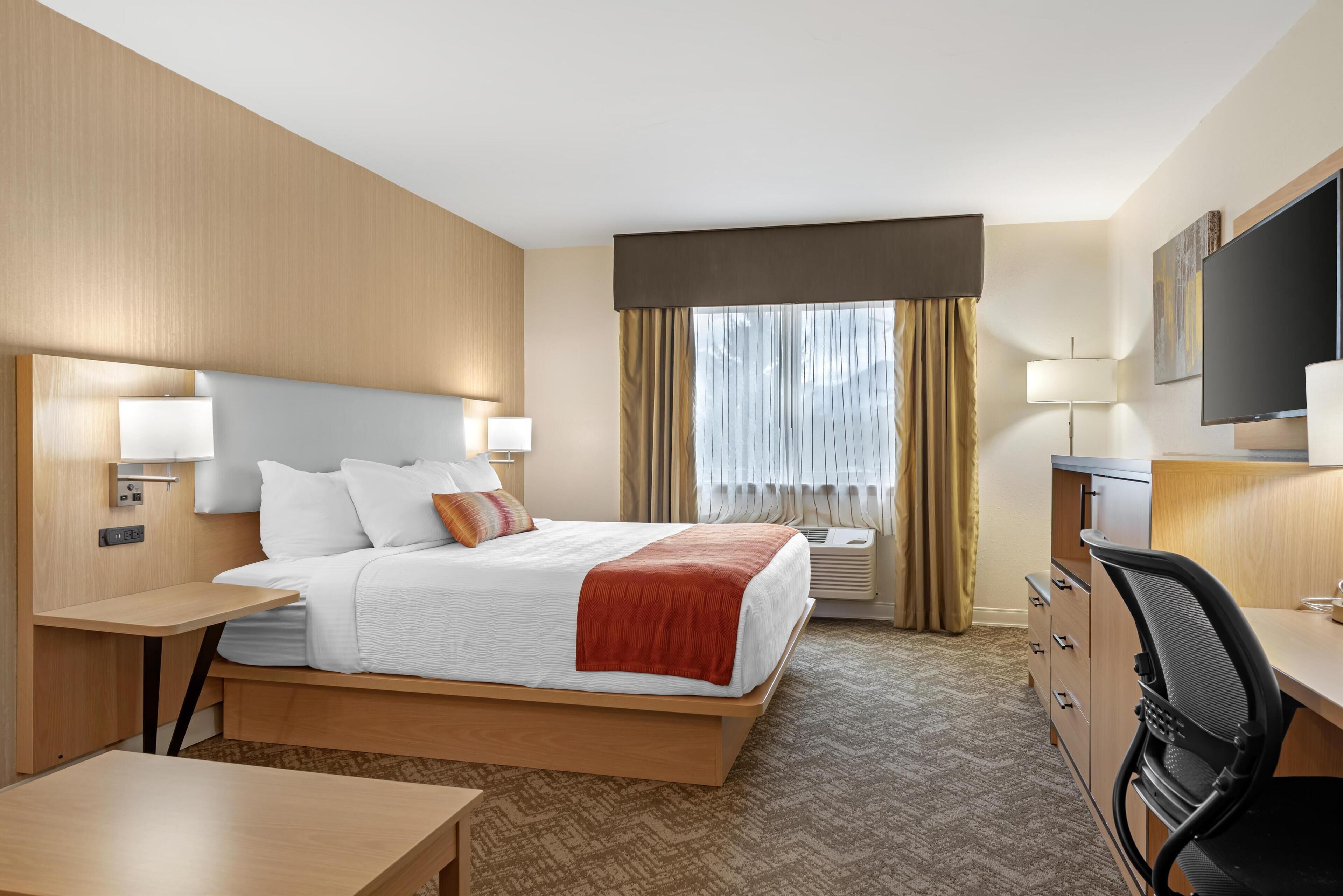 Ein Hotelzimmer mit Bett, Schreibtisch, Stuhl und Fernseher.