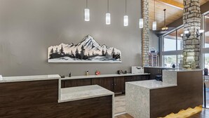 A modern kitchen with a stone pillar, wooden cabinets, and a large mountain artwork on the wall. - Best Western Vista Inn (Buena Vista)