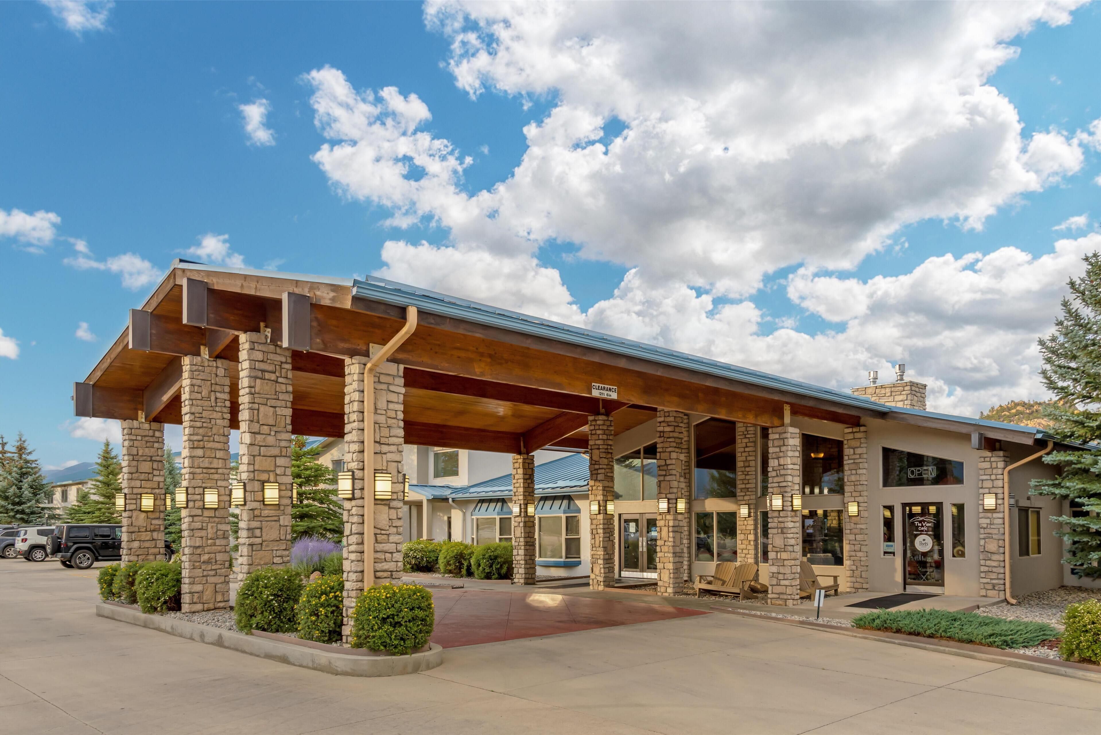 A modern building with a covered entrance, stone pillars, and a sign indicating a restaurant.