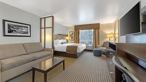 A hotel room with a bed, a sofa, a desk, a TV, and a large window with curtains. - Best Western Vista Inn (Buena Vista)