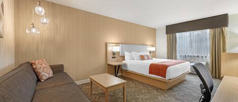 A hotel room with a bed, a sofa, a desk, and a small table.