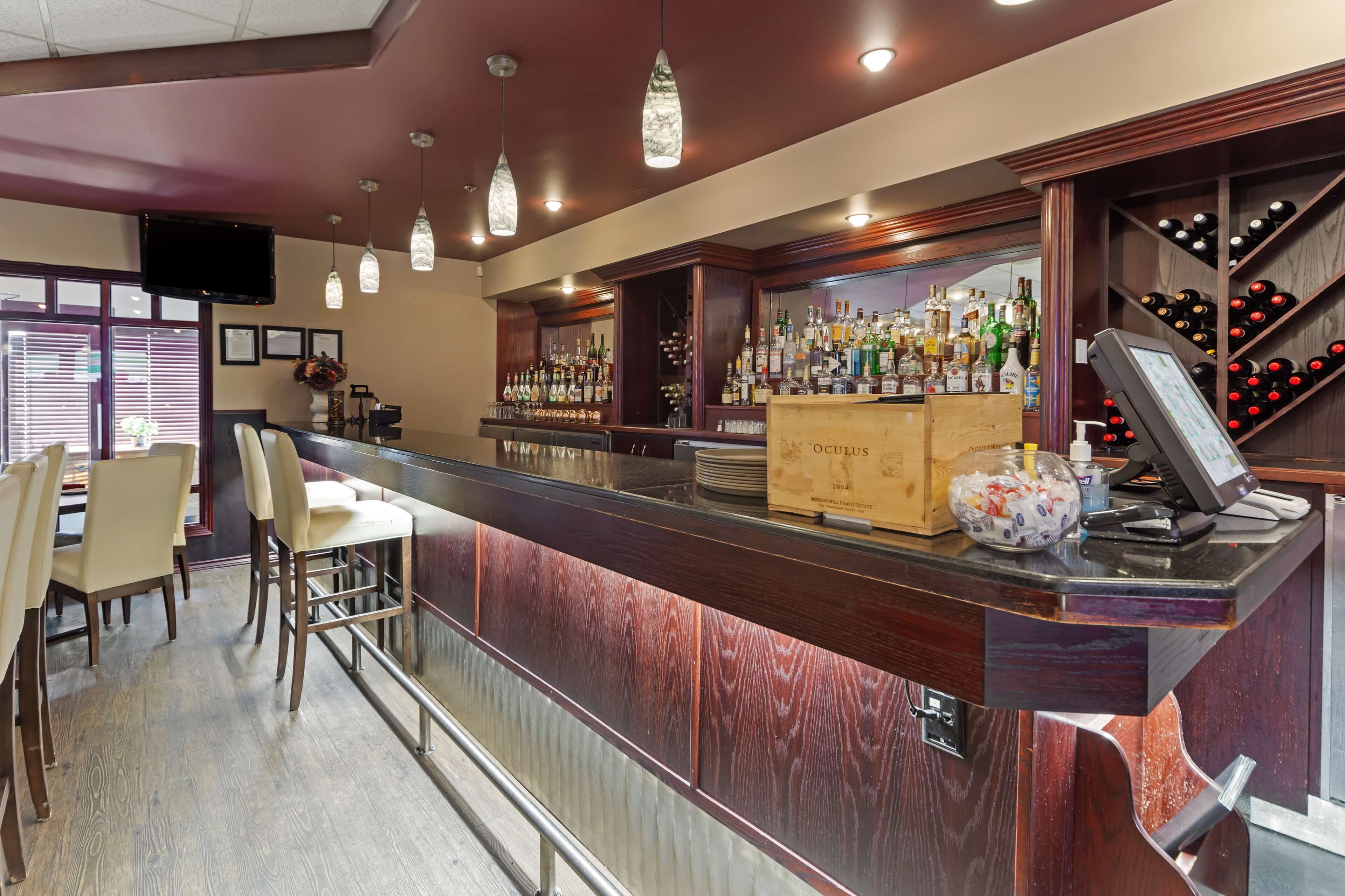 Eine Bar mit einem Holzboden, Barhocker und einem Weinkühlschrank.