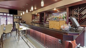 Eine Bar mit einem Holzboden, Barhocker und einem Weinkühlschrank.