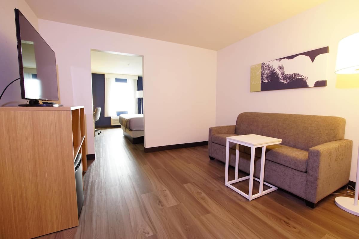A modern living room with a flat-screen TV, a sofa, a small table, and a lamp.