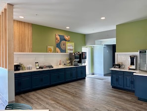 A modern kitchen with dark blue cabinets, a white countertop, and a wooden floor.