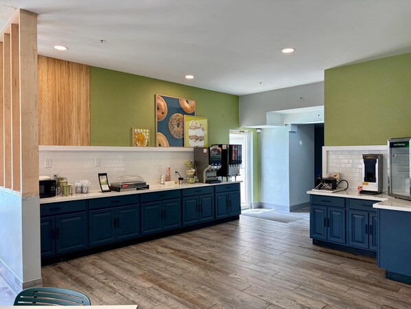 Una cocina moderna con armarios azul oscuro, encimera blanca y suelo de madera.