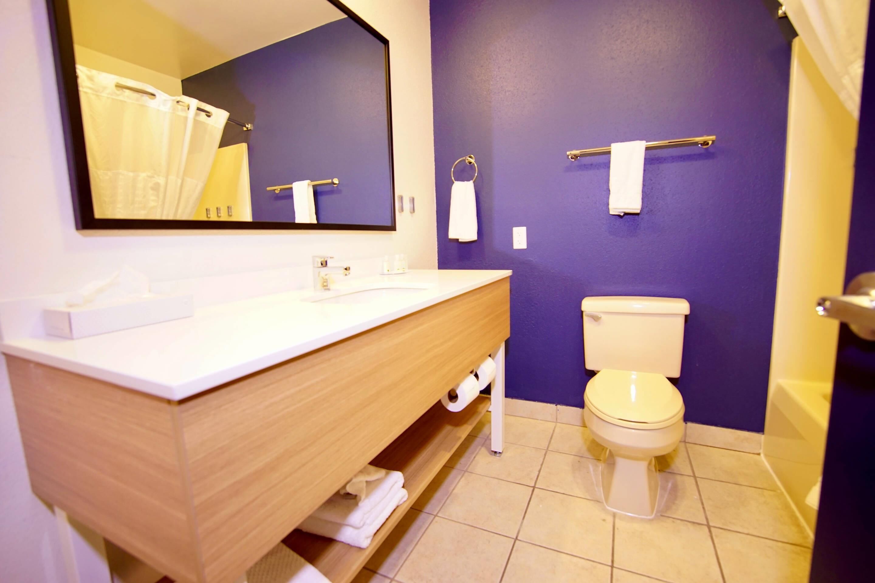 Un baño con tocador de madera, inodoro, bañera y espejo.