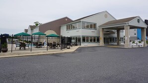 A building with a covered entrance, outdoor seating, and a fenced patio area.