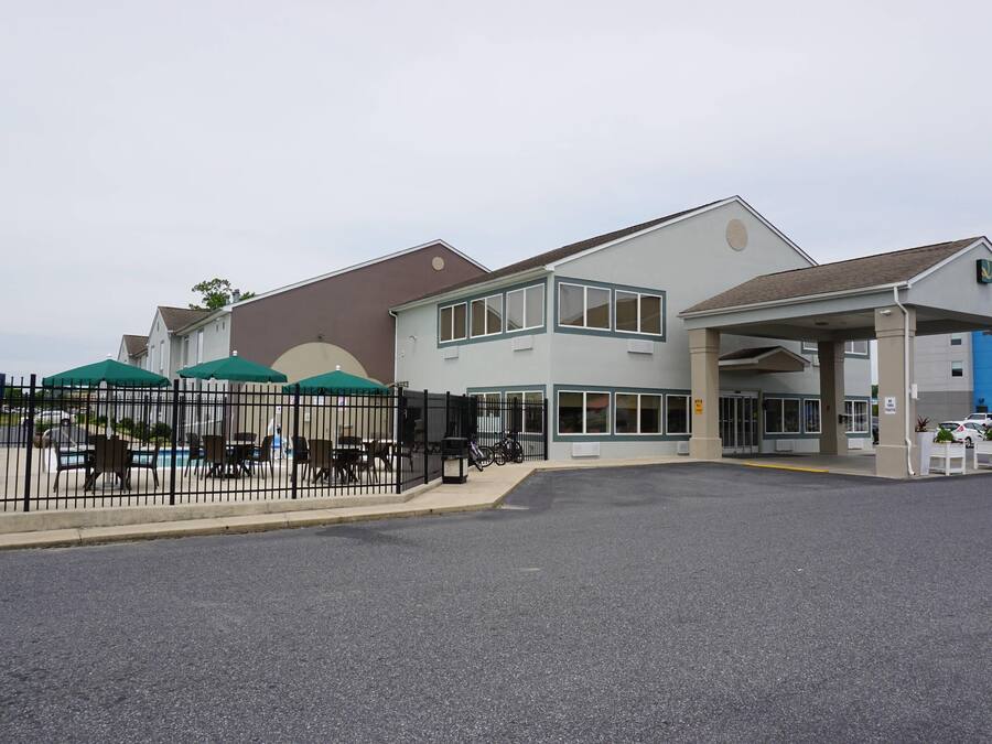 A building with a covered entrance, outdoor seating, and a fenced patio area.