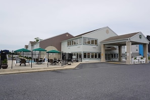 A building with a covered entrance, outdoor seating, and a fenced patio area.