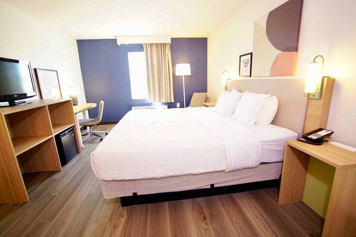 Une chambre d’hôtel équipée d’un lit, d’un bureau, d’une chaise, d’une télévision et d’une table de chevet.