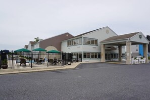 A building with a covered entrance, outdoor seating, and a fenced patio area. - Quality Inn & Suites Georgetown - Seaford (Georgetown)