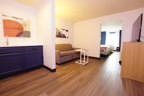 A modern living room with a sofa, a small table, and a wooden floor. - Quality Inn & Suites Georgetown - Seaford (Georgetown)