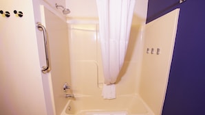 A bathroom with a bathtub, a shower curtain, a grab bar, and a towel rack. - Quality Inn & Suites Georgetown - Seaford (Georgetown)