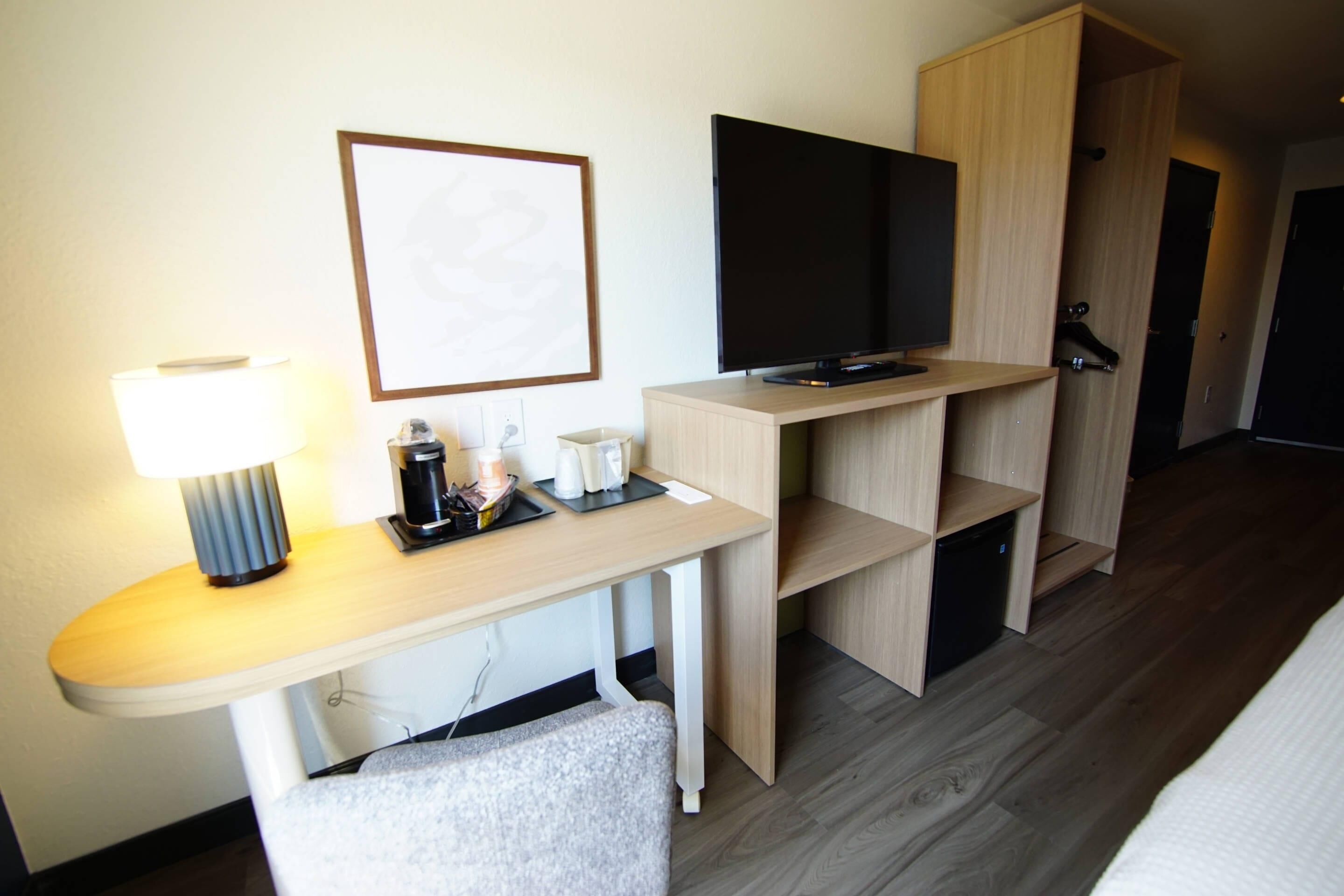 Une chambre d’hôtel équipée d’un bureau, d’un téléviseur à écran plat, d’un tableau encadré au mur et d’une armoire.